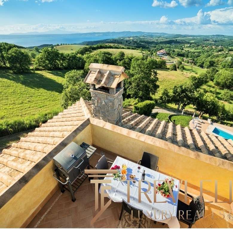 Планировка с террасы с видом на зеленую сельскую местность и море у горизонта, роскошный дом на холме с террасой и камином, популярное место для отдыха и развлечений.