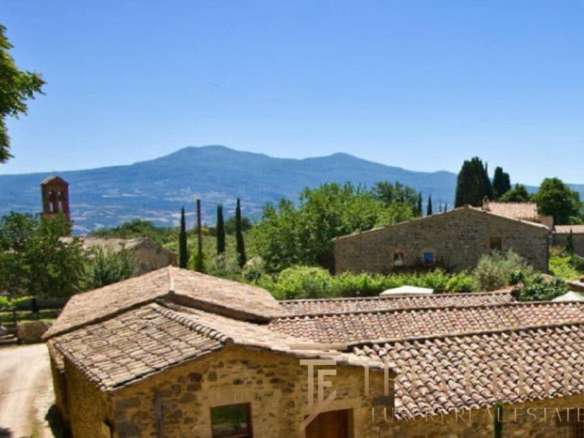 Восхитительный вид на итальянский деревенский пейзаж с крытыми черепичной кровлей домами и зеленью, окружёнными горами и кедровыми деревьями.