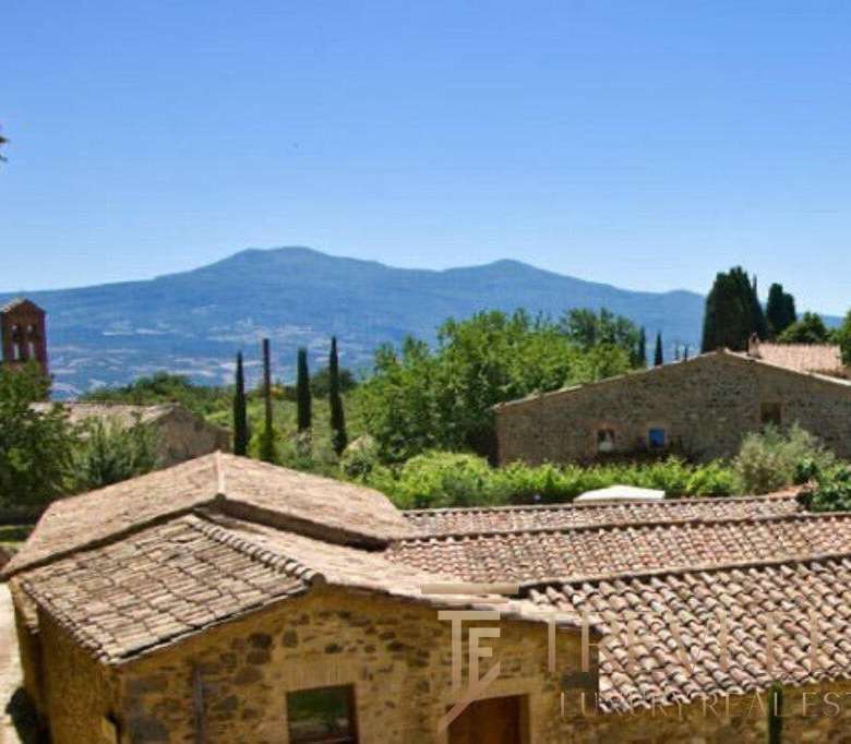 Восхитительный вид на итальянский деревенский пейзаж с крытыми черепичной кровлей домами и зеленью, окружёнными горами и кедровыми деревьями.