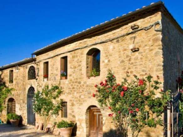 Уникальный каменный дом в Тоскане, Италия, окружён садом с цветущими деревьями и яркими розами, идеально подходит для роскошной покупки у агентства недвижимости Треви Элит.