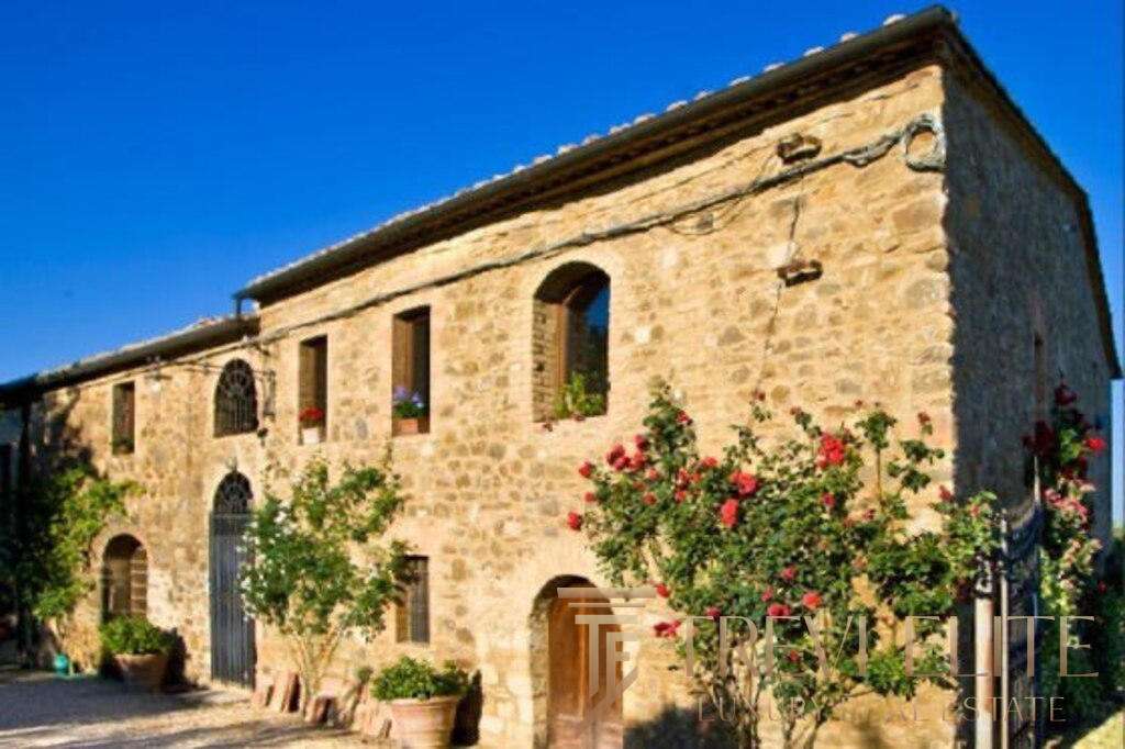 Уникальный каменный дом в Тоскане, Италия, окружён садом с цветущими деревьями и яркими розами, идеально подходит для роскошной покупки у агентства недвижимости Треви Элит.