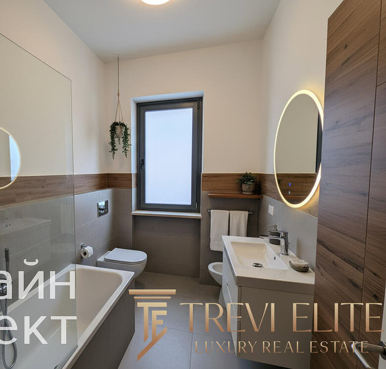 современный стиль ванной комнаты с белой сантехникой и деревянными панелями, просторное помещение с окном и зеркалами с подсветкой, дизайн интерьера в эко-стиле для элитной недвижимости.