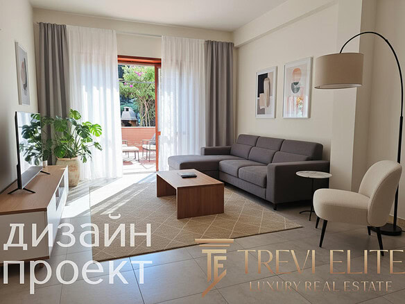 Современная гостиная с мягким серым диваном, декоративными картинами, светлыми шторами и частным балконом на заднем плане, создающая уютную атмосферу для комфортного проживания.