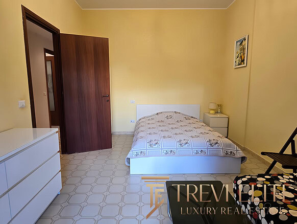 Современная спальня в роскошной квартире, минималистский дизайн, светлые стены, удобная кровать, мебель из светлого дерева, приятная атмосфера, идеально подходит для отдыха.