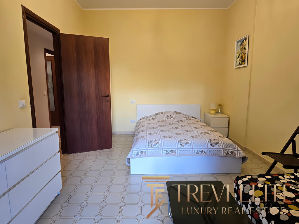 Современная спальня в роскошной квартире, минималистский дизайн, светлые стены, удобная кровать, мебель из светлого дерева, приятная атмосфера, идеально подходит для отдыха.