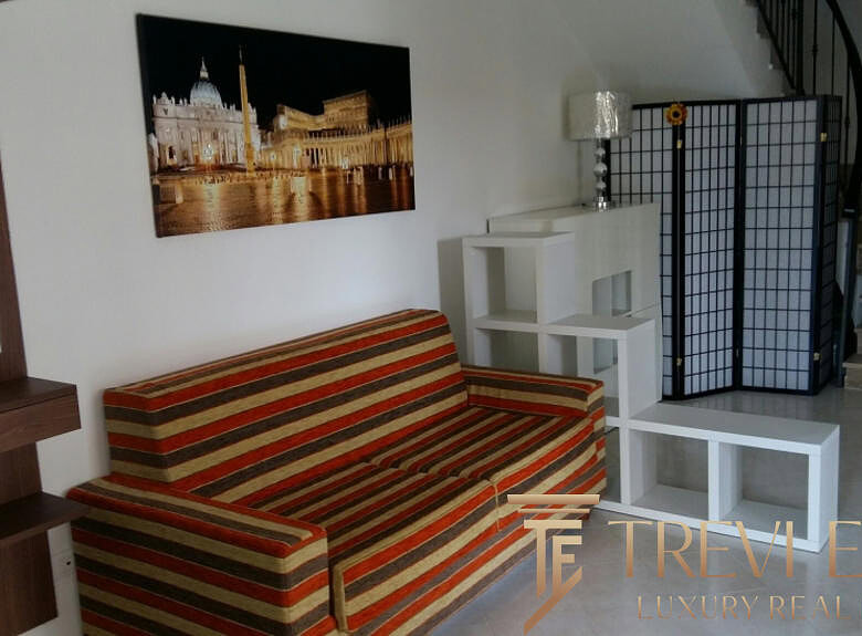 Высококачественное изображение уютного интерьера современного жилого пространства с комфортабельным диваном, декорированным панно, светильником и современной мебелью, которое демонстрирует профессиональные услуги агентства недвижимости Треви Элит.