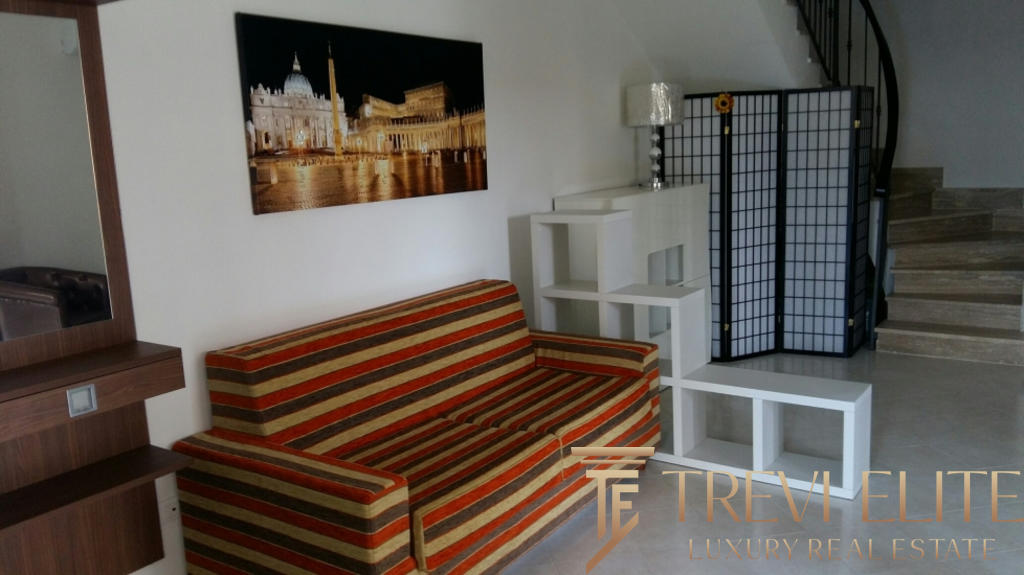 Высококачественное изображение уютного интерьера современного жилого пространства с комфортабельным диваном, декорированным панно, светильником и современной мебелью, которое демонстрирует профессиональные услуги агентства недвижимости Треви Элит.