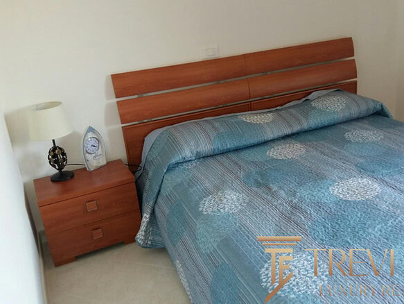 Современная спальня с деревянной кроватью и голубым постельным бельем в уютной комнате для комфортного отдыха.