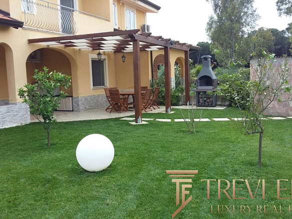 Красивый ухоженный двор с зоной барбекю и зеленой травой, окруженный деревьями и уютной террасой, идеально подходит для отдыха и проведения мероприятий.