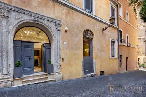 Ochre travertine palazzo facade with arched blue entrance, Rome