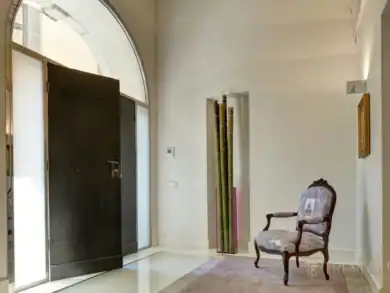 Luminous entrance hall with arched doorway and exposed timber ceiling, Rome palazzo