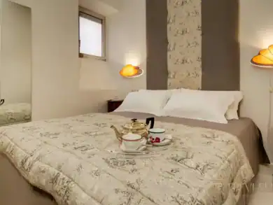 Minimalist bedroom with travertine accent wall and designer lighting, Rome