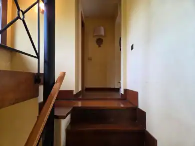 Elegant staircase with wooden steps and wrought-iron railing, cream walls
