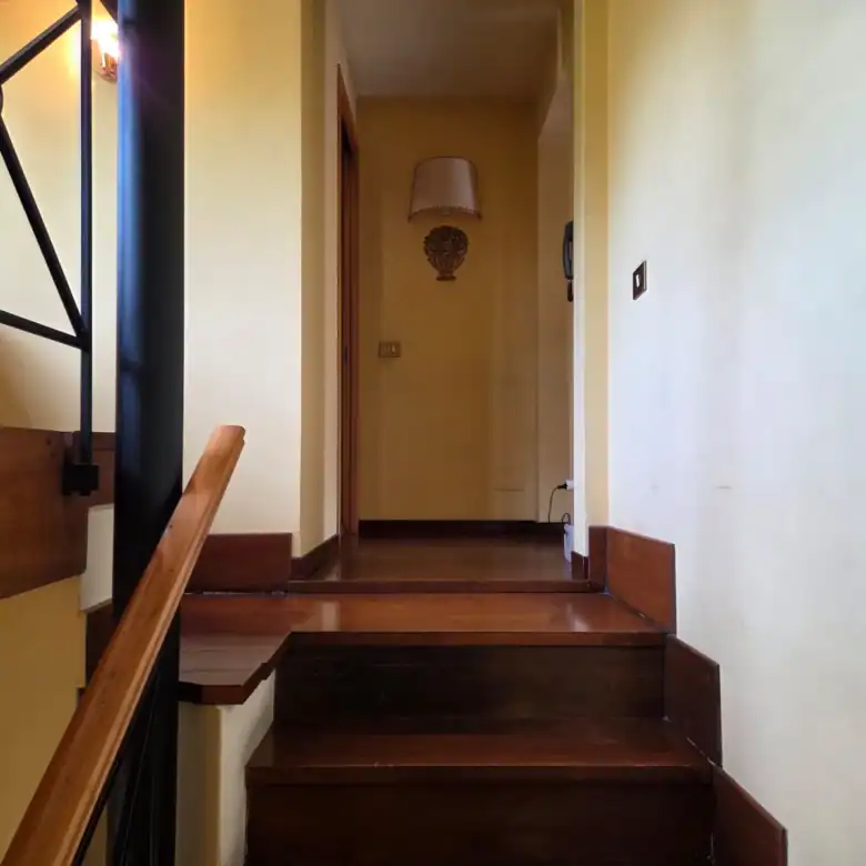 Elegant staircase with wooden steps and wrought-iron railing, cream walls